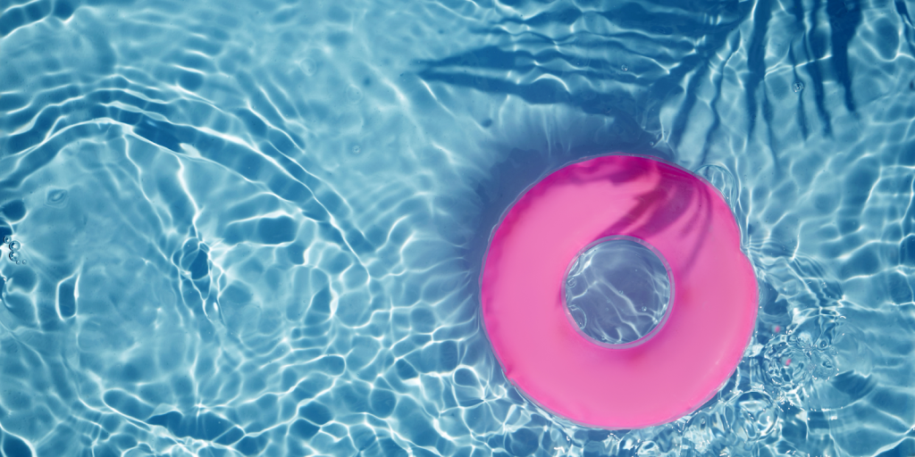 Bright pink pool float drifting in clear blue water with sunlight reflecting on the surface.