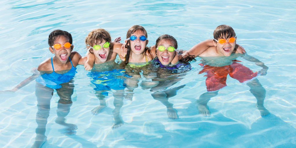 Children swimming together in a clear commercial swimming pool, supervised environment promoting pool safety and water quality.