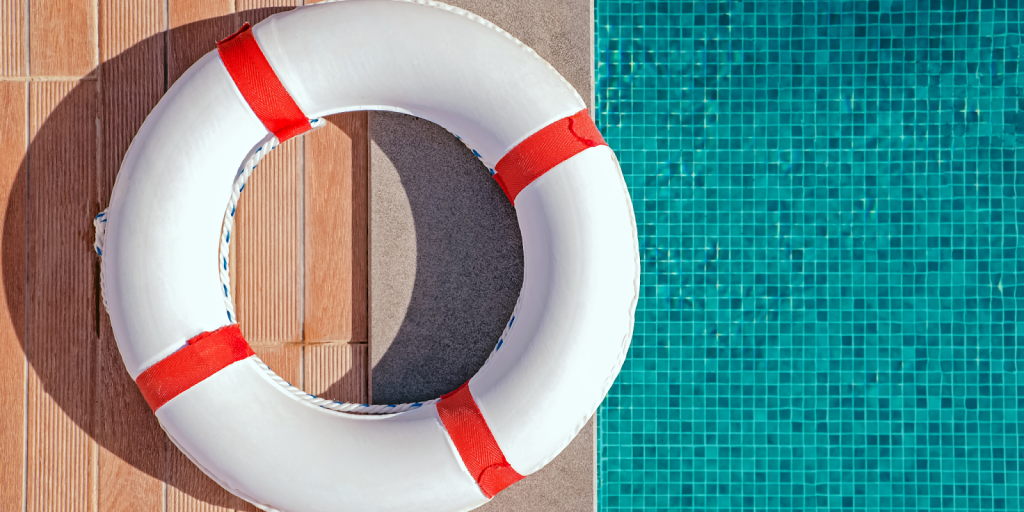 Life ring safety equipment placed beside a commercial swimming pool as part of required pool safety regulations.