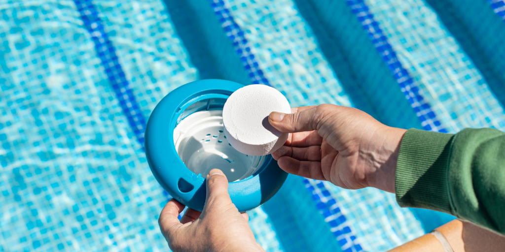 Pool maintenance staff placing chlorine tablet into floating dispenser to maintain safe water quality in a commercial swimming pool.