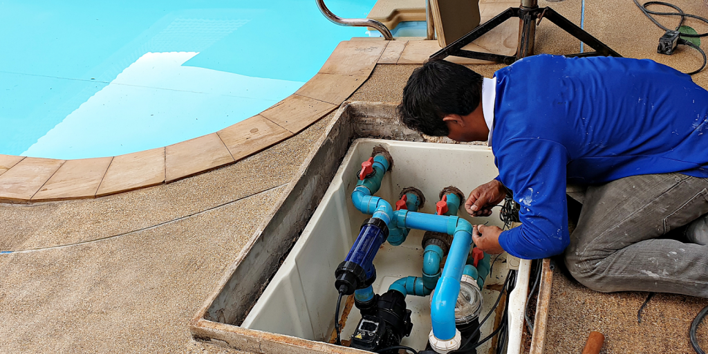 Pool maintenance technician servicing commercial pool pump and filtration system to ensure efficient pool operations.