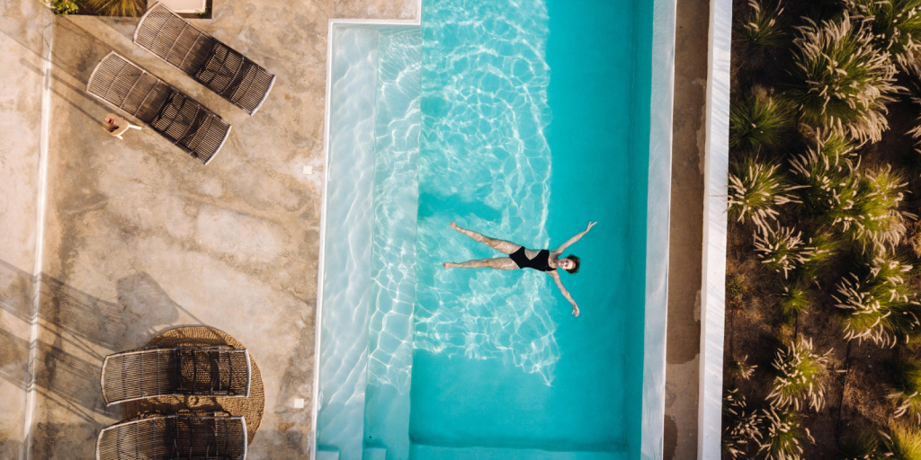 Aerial view of person floating in a clean rectangular swimming pool.