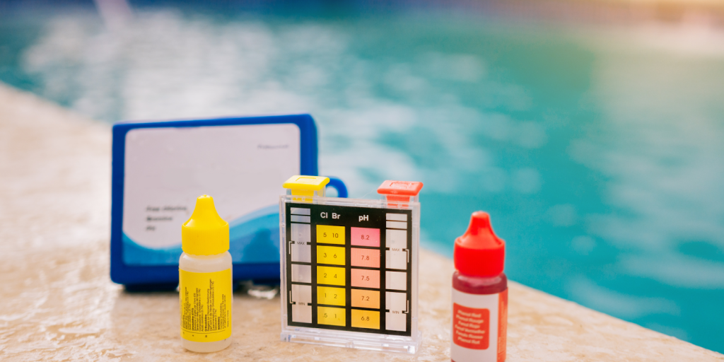 Pool water testing kit with chlorine and pH color chart beside swimming pool.
